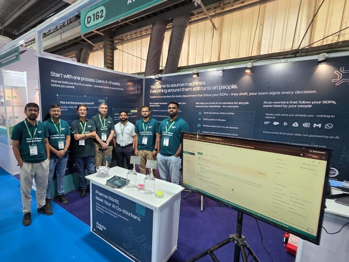 The Avesta Labs stand at PharmaTech Expo 2026 seen from the aisle, its D 162 sign overhead, the team along the front and a demo screen on a tripod at the right